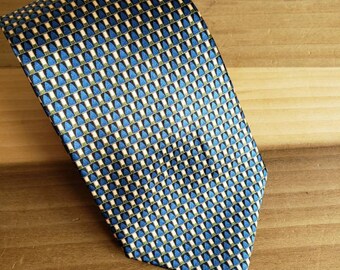 May include: A blue, green, and white patterned silk tie. The pattern is a repeating geometric design.