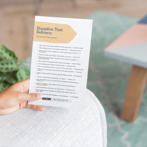 Może przedstawiać: Biała karta z tytułem "Discipline That Delivers: Self-Control That Works" jest trzymana. Karta zawiera listę tekstu. Doniczka i mały stolik są widoczne w tle.