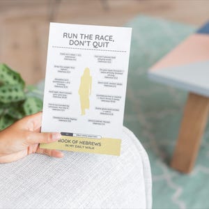 Può includere: Una carta bianca con il testo "RUN THE RACE, DON'T QUIT" e versetti biblici. La carta ha una silhouette gialla di una persona ed è tenuta da una persona. La carta fa parte della serie "BOOK OF HEBREWS IN MY DAILY WALK".