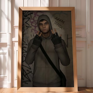 以下が含まれることがあります： グレーのパーカーと黒い手袋をした人物が、手のジェスチャーをしている額入りのアートワーク。背景には「AAAM TENEA」という文字の落書きアートが描かれています。フレームは明るい茶色の木製です。