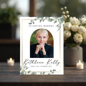 Op de afbeelding: Een herdenkingskaart met een gouden rand en de woorden "In Loving Memory". De kaart toont een foto van een vrouw, met de naam "Kathleen Kelly" en de data "April 1955- oktober 2025" eronder. Groen accentueert de boven- en onderkant.