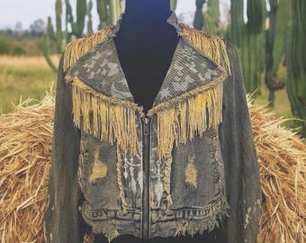 May include: A denim jacket with a fringed collar and distressed details. The jacket is decorated with white paint and has a zipper closure.