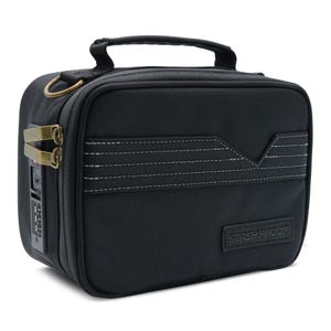 Puede incluir: Bolso rectangular negro con asa y cerradura de combinación. El bolso tiene una superficie texturizada con detalles de costura blancos y un cierre color latón. El texto "STASHPROOF" es visible.