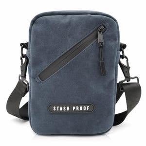 May include: A blue crossbody bag with a black zipper and strap. The bag has the text "STASH PROOF" on the front. The bag has a rectangular shape and is designed to be worn over the shoulder.