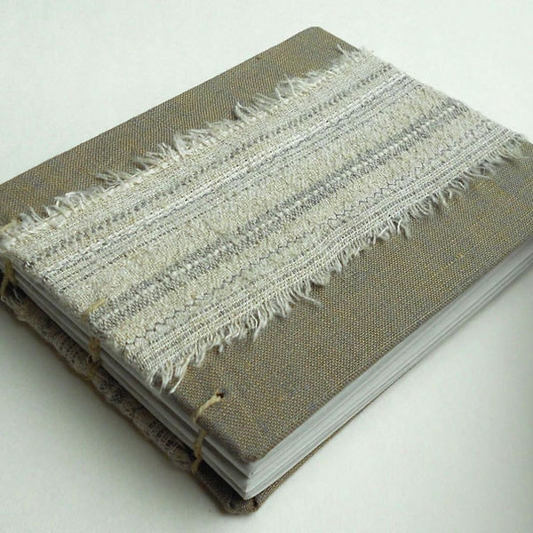 Torn fabric covered blank book in gray hues.