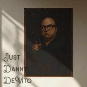 Peut inclure: Un portrait encadré de Danny DeVito, portant des lunettes et une chemise noire, tenant une arme à feu. L'arrière-plan présente un motif floral sombre. Les mots "Just Danny DeVito" sont imprimés dans une police décorative.