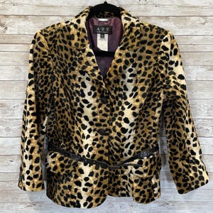 Pode incluir: Blazer com estampa de leopardo e cinto preto. O casaco tem gola clássica, três botões pretos e um cinto preto que aperta na cintura. O forro é de cor roxa escura.