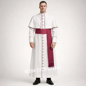 May include: A white clerical robe with a matching cape, accented with burgundy trim and buttons. A burgundy sash is worn around the waist. The robe is worn with black shoes.