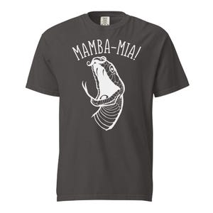 Puede incluir: Camiseta gris oscuro con un gráfico blanco de la boca abierta de una serpiente y el texto "MAMBA-MIA!". El diseño está centrado en la parte delantera de la camiseta de manga corta, hecha de un material suave y cómodo.