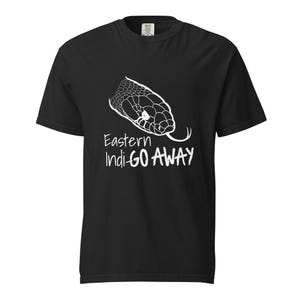 Puede incluir: Camiseta negra con un gráfico blanco de la cabeza de una serpiente y el texto "Eastern Indi GO AWAY". La cabeza de la serpiente está detallada con escamas y una lengua bífida. La camiseta tiene cuello redondo.