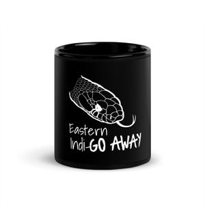 May include: Black ceramic mug with a white illustration of an Eastern Indigo snake head. The text "Eastern Indi-GO AWAY" is printed below the snake image in white. A novelty item.