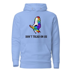May include: Pale blue hoodie with a front pocket and a hood. The hoodie displays a colourful snake graphic and the text "DON'T TREAD ON US" in black. The snake graphic is in rainbow colours.