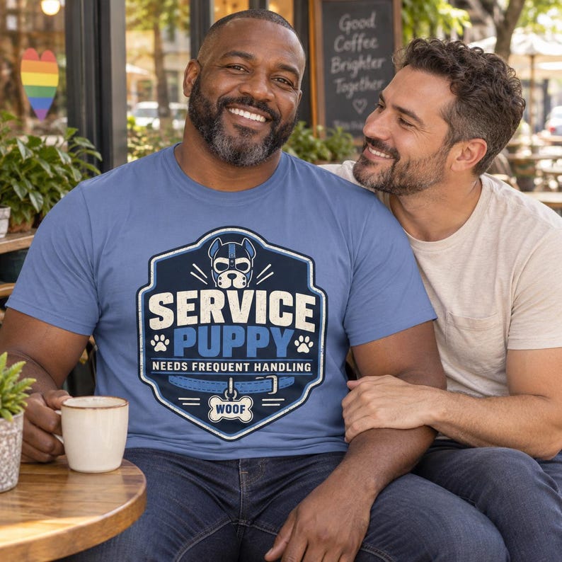 K&ouml;nnte beinhalten: Ein blaues T-Shirt mit einem grafischen Design eines Hundekopfes mit Geschirr, dem Text "SERVICE PUPPY" und "NEEDS FREQUENT HANDLING", einer Halsbandillustration und einer knochenf&ouml;rmigen Marke mit dem Wort "WOOF" in der Mitte des Wappens.