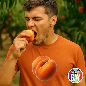 May include: An orange t-shirt with a large peach graphic. The shirt features the text "Your Shirt Is GAY" in a circular design. A person is shown eating a peach in a peach orchard.
