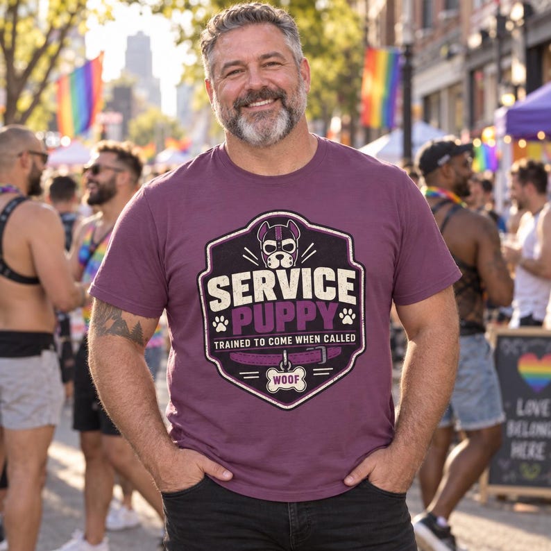 K&ouml;nnte beinhalten: Ein pflaumenfarbenes T-Shirt mit einer Grafik einer Hundemaske in einem schildf&ouml;rmigen Emblem. Der Text lautet SERVICE PUPPY, TRAINED TO COME WHEN CALLED und WOOF auf einem knochenf&ouml;rmigen Anh&auml;nger. Ein violettes Halsband ist darunter abgebildet.