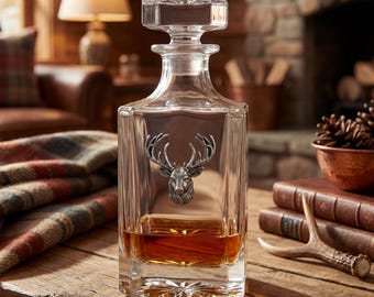 May include: A clear glass decanter with a silver stag head emblem. The decanter is filled with amber liquid and has a square shape with a stopper. The background includes a wooden table, books, and a fireplace, creating a rustic aesthetic.