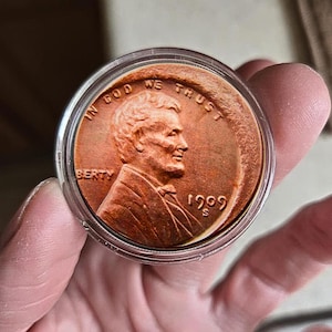 May include: A copper-colored 1909 S Lincoln cent coin, encased in a clear protective holder. The coin features a profile of Abraham Lincoln and the inscriptions "IN GOD WE TRUST" and "LIBERTY".