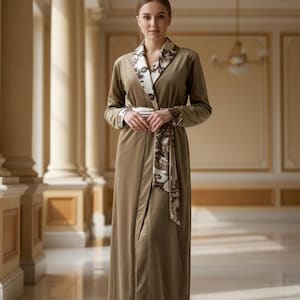 May include: An olive-green dressing gown with a shawl collar and matching belt. The collar, cuffs, and belt have a cream-coloured fabric with a brown paisley design. The robe is made of a soft, velvety material.