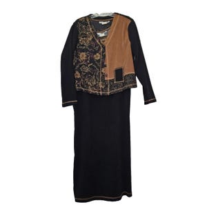 May include: A black dress with a long-sleeved top and a vest. The vest has a brown suede panel and a floral pattern on the other panel. The dress is a midi length with a brown trim at the hem.