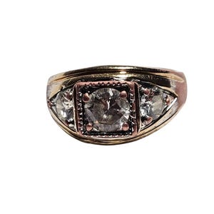 May include: A gold and silver ring with a large clear stone surrounded by smaller clear stones.