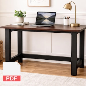 May include: A rectangular wooden desk with a dark brown top and black legs. A laptop, a potted plant, a lamp, and a pencil holder are on the desk. The laptop screen displays a landscape image. The desk is in a well-lit room.