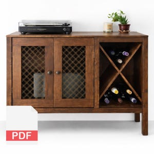 May include: A wooden wine cabinet with a built-in wine rack and cabinet doors with a decorative mesh design. A record player sits on top, along with a small potted plant and a candle. The cabinet is stained a warm brown color.