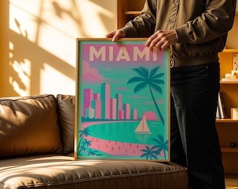 Puede incluir: Una impresión artística enmarcada que presenta una escena de viaje de Miami. La obra de arte muestra la palabra "MIAMI" sobre una colorida representación del horizonte de la ciudad, palmeras y un velero. La paleta de colores incluye tonos rosas, turquesas y naranjas.