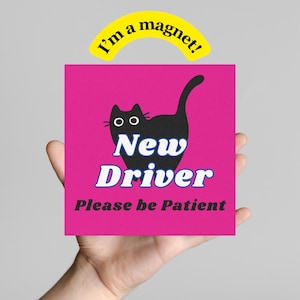 May include: A pink square magnet with a black cat illustration and the words "New Driver Please be Patient" in white and blue. A yellow arched magnet above reads "I'm a magnet!"