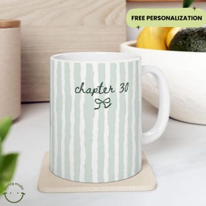 May include: White ceramic mug with a green and white striped pattern. The mug features the text "chapter 30" with a bow graphic. The mug is on a beige coaster. The words "FREE PERSONALIZATION" are in the background.