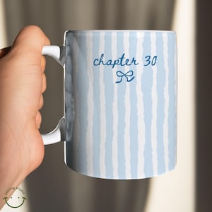 May include: White ceramic mug with a blue and white striped pattern. The mug features the text "chapter 30" in a script font with a bow graphic. The mug is held by a hand.