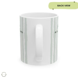 May include: White ceramic mug with a curved handle, featuring vertical light green brushstroke stripes. The mug has handwritten text in black ink. The words "I love my dreams" are visible on the side of the mug. The mug is a back view.