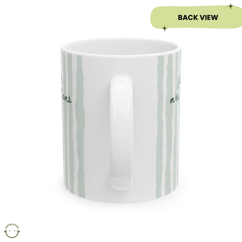 May include: White ceramic mug with a curved handle, featuring vertical light green brushstroke stripes. The mug has handwritten text in black ink. The words "I love my dreams" are visible on the side of the mug. The mug is a back view.