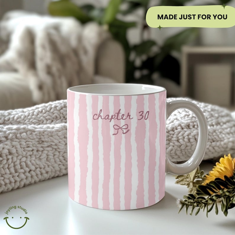 May include: A white ceramic mug with a pink and white striped pattern. The mug features the text "chapter 30" in a cursive font, with a bow graphic. The mug has a white handle and a light gray rim.