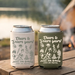 Peut inclure: Deux refroidisseurs de canettes, un crème et un vert olive, avec le texte "Cheers to S'more years!" et "Jamie's 20th Birthday Jackson Hole, Wyoming." Les refroidisseurs ont des illustrations sur le thème du camping.
