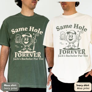 Puede incluir: Dos camisetas con el texto "Same Hole Forever" y un personaje de pelota de golf sosteniendo una cerveza y un palo de golf. Una camiseta es verde musgo con una impresi&oacute;n marfil, la otra es marfil con una impresi&oacute;n musgo. El texto "Jack's Bachelor Par-Tee" est&aacute; debajo.