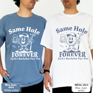 Puede incluir: Dos camisetas, una azul y otra blanca, con un dise&ntilde;o tem&aacute;tico de golf. El dise&ntilde;o incluye el texto "Same Hole Forever" con un personaje de bola de golf de dibujos animados sosteniendo una cerveza y un palo de golf. Tambi&eacute;n se incluye el texto "Jack's Bachelor Par-Tee".