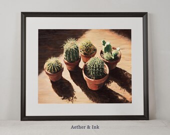 May include: A framed print showing five cacti in terracotta pots on a wooden surface. The cacti have different shapes and textures. The image is framed in black, with the text "Aether & Ink" at the bottom. The print is a decorative item.