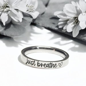 May include: A silver ring with the words "Just Breathe" and a small heart engraved on the band.