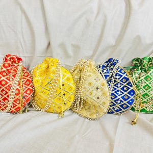May include: Five colourful drawstring pouches in red, yellow, gold, blue, and green. Each pouch features a geometric pattern with gold accents and is adorned with a pearl beaded trim and drawstring. The pouches are arranged on a white fabric.