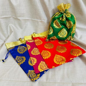 Peut inclure: Plusieurs sacs à cordon colorés en rouge, bleu, rose et vert. Chaque sac présente un motif floral doré et une bordure dorée. Les sacs sont faits d'un tissu brillant.