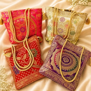 May include: Four square tote bags featuring intricate woven patterns in vibrant pink, cream, red, and purple. Each bag has gold-toned rope handles and decorative tassels at the corners, showcasing detailed floral and geometric motifs throughout.