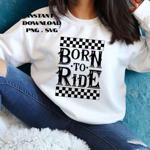 Könnte beinhalten: Weißes Sweatshirt mit dem Text "BORN TO RIDE" in schwarzer, fetter Schrift, umrahmt von schwarz-weißen Schachbrettmustern. Über dem Haupttext steht "INSTANT DOWNLOAD PNG . SVG". Das Sweatshirt wird mit blauen Jeans kombiniert.