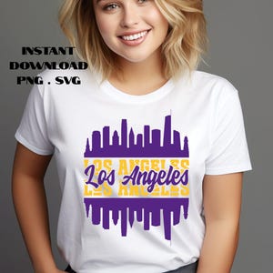 May include: White t-shirt featuring a purple and gold Los Angeles skyline design. The text "Los Angeles" is displayed in a stylized font. The words "Instant Download PNG. SVG" are printed at the top.