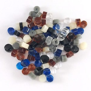 May include: A collection of colorful glass and plastic beads in various shapes and sizes. The beads are a mix of blue, red, brown, white, gray, and clear.