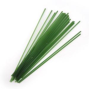 May include: A bundle of thin, green glass rods, approximately 12 inches long, used for glassblowing or other craft projects.