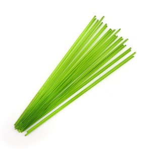 May include: A bundle of thin, green glass rods, approximately 12 inches long, for use in glassblowing or other craft projects.