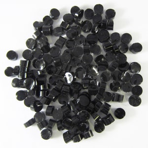 May include: A large pile of black plastic pellets. The pellets are small and round, and they are all the same size.