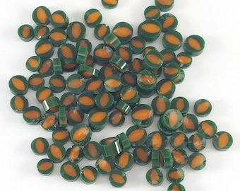 May include: A large group of green and orange oval-shaped beads. The beads are made of a smooth, glossy material and have a slightly raised design.