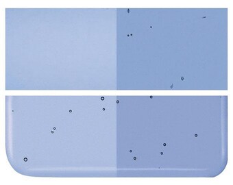 May include: A close-up of a light blue surface with small, dark blue circles scattered across it. The surface is divided into two sections, with the left side being slightly lighter than the right side.