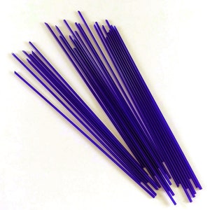 May include: A bundle of thin, purple glass rods, ideal for glassblowing or crafting projects.